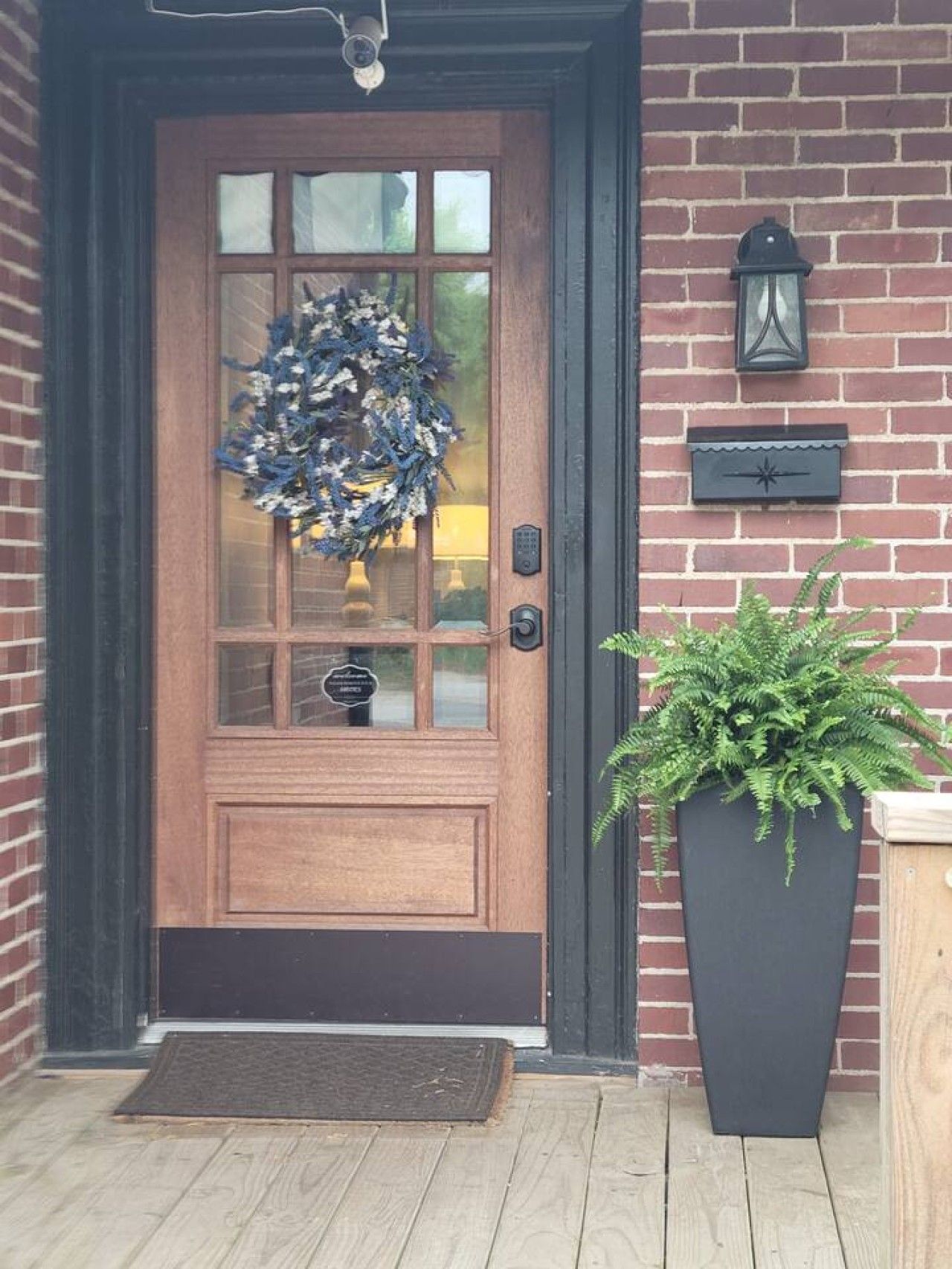 A wooden front door with a wreath, a mailbox, and a potted plant.