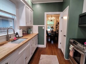 A kitchen with white cabinets, a stainless steel sink, and a built-in oven. - Park Hill Retreat Dog Friendly (Fort Smith)