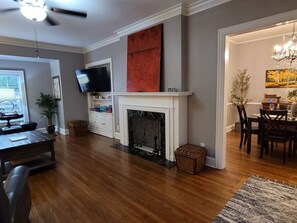 A living room with a fireplace, a television, and a dining area with chairs and a table. - Park Hill Retreat Dog Friendly (Fort Smith)