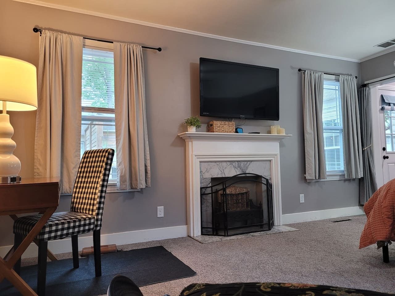 A living room with a fireplace, a television mounted above it, and a chair.