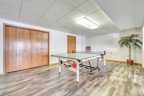 Ein Zimmer mit einem Tischtennisplatte, Holzboden, einer Topfpflanze und einer Tür mit dekorativem Griff.
