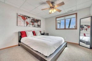 Una camera da letto con un letto, una ventola a soffitto, una finestra e opere d'arte alle pareti.