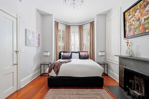 Ein Schlafzimmer mit einem großen Bett, einem Kamin und einem Gemälde an der Wand.