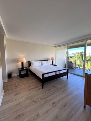 A bedroom with a bed, bedside tables, and a balcony with a view. - Ocean View One Bedroom, Two Bath Condo - Steps from Beach - The Whaler 624 (Lahaina)