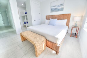 A neatly arranged bedroom with a bed, a bench, a bedside table with a lamp, and a door leading to a bathroom. - Ocean Views • Private Pool and Spa • 12 Sleeping Rooms • Sleeps 28 (North Myrtle Beach)