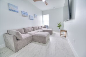 A modern living room with a sectional sofa, a small wooden side table, and a potted plant. - Ocean Views • Private Pool and Spa • 12 Sleeping Rooms • Sleeps 28 (North Myrtle Beach)