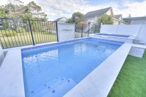 A rectangular swimming pool with blue tiles, surrounded by a white wall and a metal fence. - Ocean Views • Private Pool and Spa • 12 Sleeping Rooms • Sleeps 28 (North Myrtle Beach)