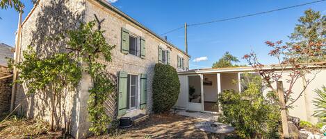 Un bâtiment en pierre doté d’un jardin, d’une terrasse couverte et surplombant un ciel dégagé.