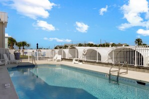 A swimming pool with clear blue water, surrounded by white railings and lounge chairs. - 🌴Snapper Landing | Steps to Beach | Pool | Pet Friendly🌴 (Mexico Beach)