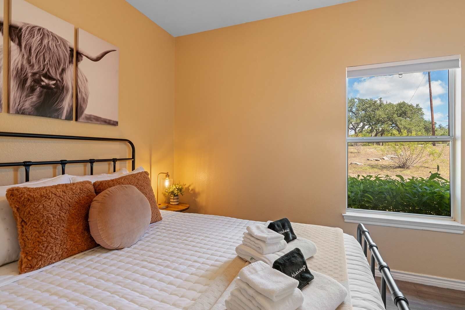 Une chambre à coucher avec un lit, des oreillers, une table de chevet, une lampe et une fenêtre donnant sur l’extérieur.