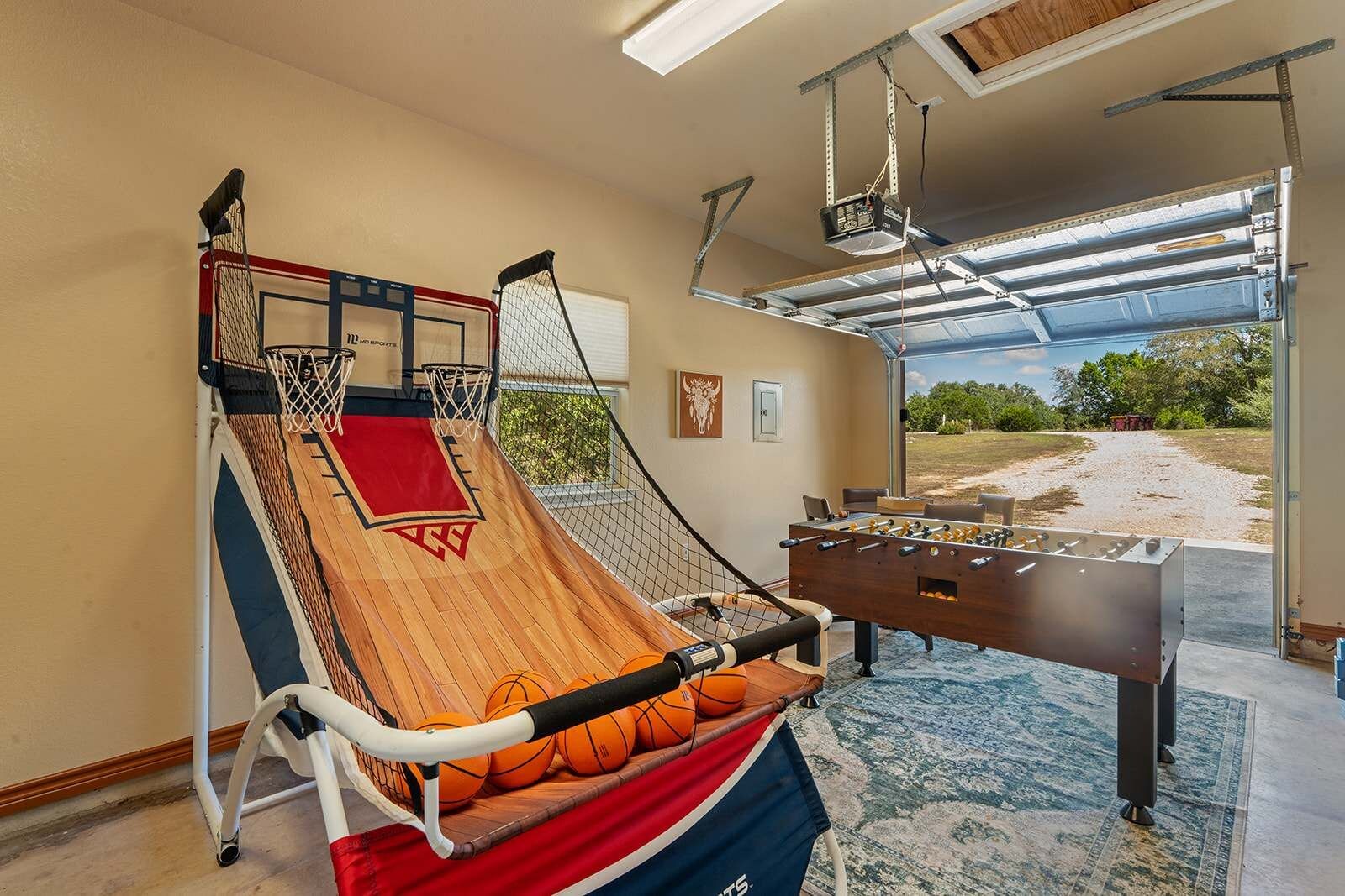 Un aro de baloncesto, una mesa de fútbol de mesa y vistas al exterior a través de una puerta de garaje.