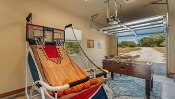 Un aro de baloncesto, una mesa de fútbol de mesa y vistas al exterior a través de una puerta de garaje.