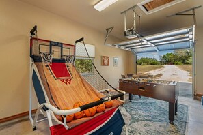 Un aro de baloncesto, una mesa de fútbol de mesa y vistas al exterior a través de una puerta de garaje.