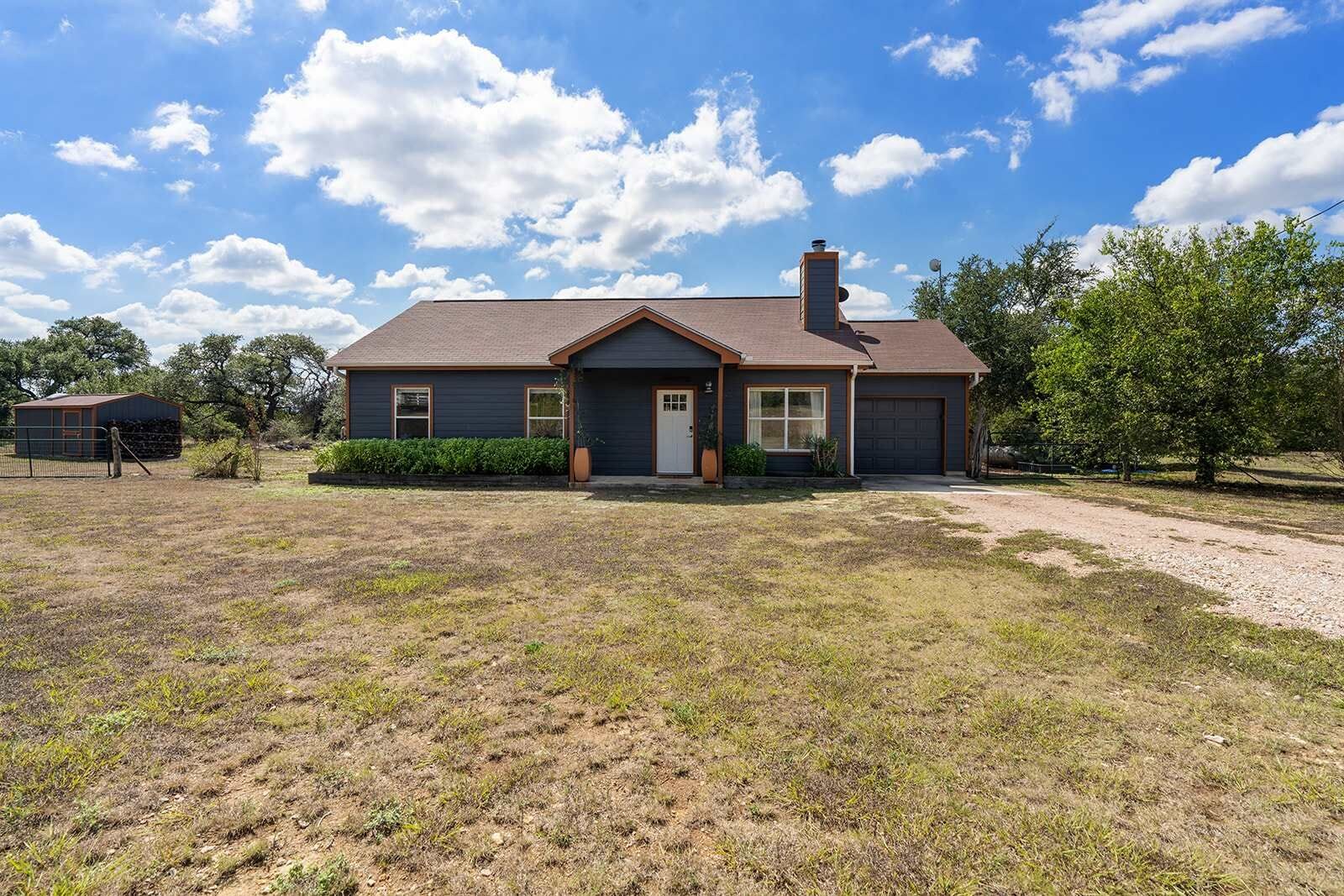 A single-story house with a front porch, a garage, and a fenced yard.