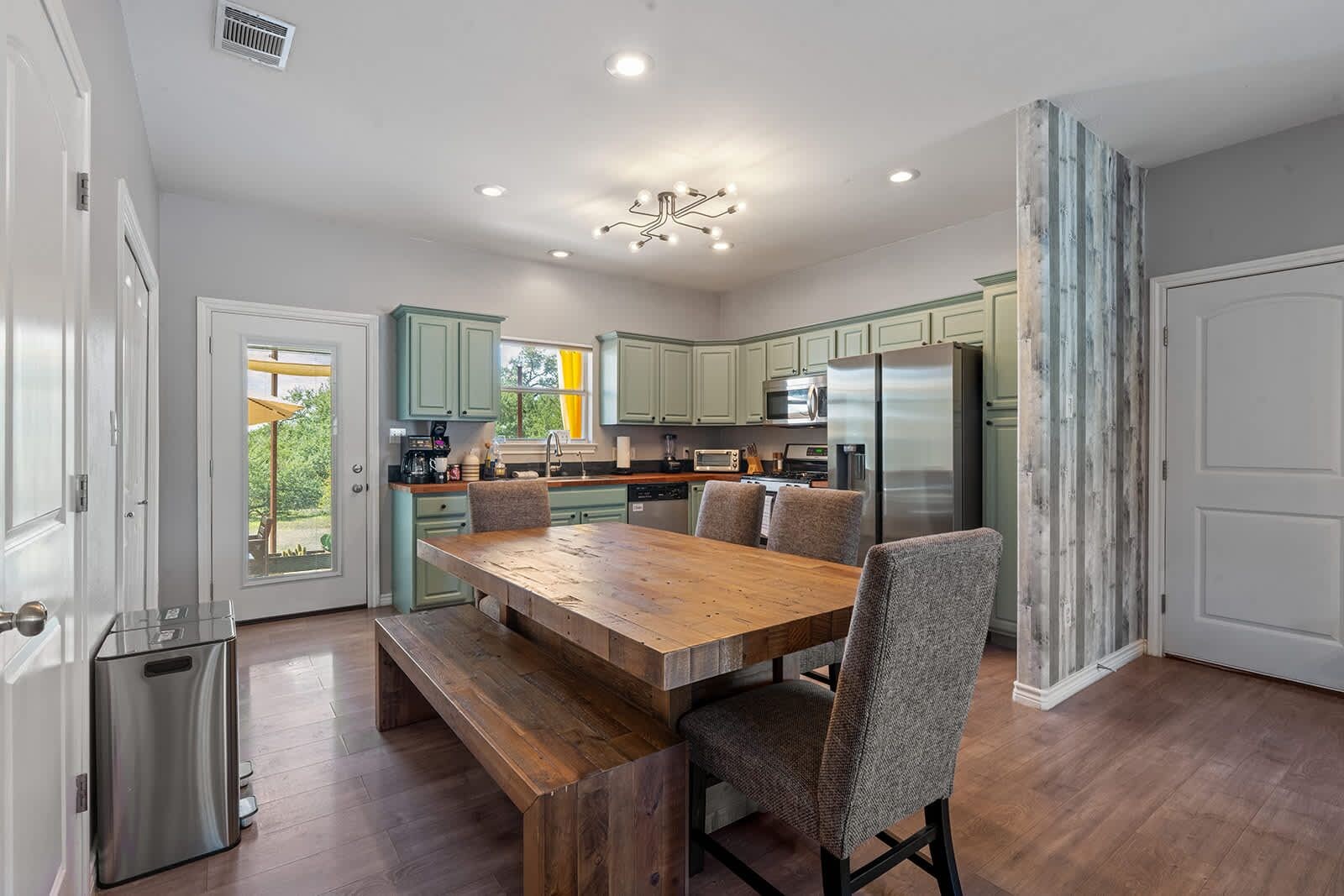 A modern kitchen with a wooden dining table, built-in appliances, and light-colored cabinetry.
