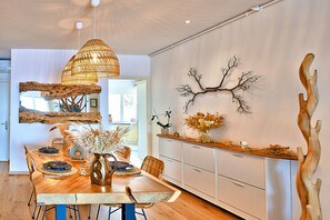 A dining area with a wooden table, chairs, and a hanging light fixture. - Le Balcon des Sanguinaires - Vue sur la mer (Ajaccio)