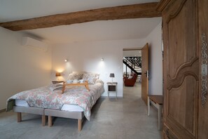 Ein Schlafzimmer mit einem Bett, Nachttischen, einem Kleiderschrank und einer Treppe, die zu einem anderen Raum führt.