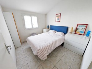 A bedroom with a bed, a nightstand, a dresser, a radiator, a window, and wall decorations. - Le Green de Pornic - A 2km du Port (Pornic)