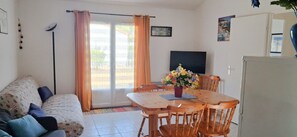 A living room with a sofa, a dining table with chairs, a TV, and a refrigerator. - Le Green de Pornic - A 2km du Port (Pornic)
