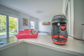 A room with a modern design, featuring a large window, a red box with a logo, and a Bosch device on a counter. - Le Studio du Champ de Foire (Treillières)