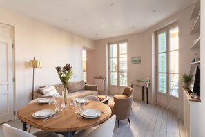 A dining area with a round table set for four, a sofa, and a chair. - Le 50 Emeraude - 200m de la Plage (Dinard)