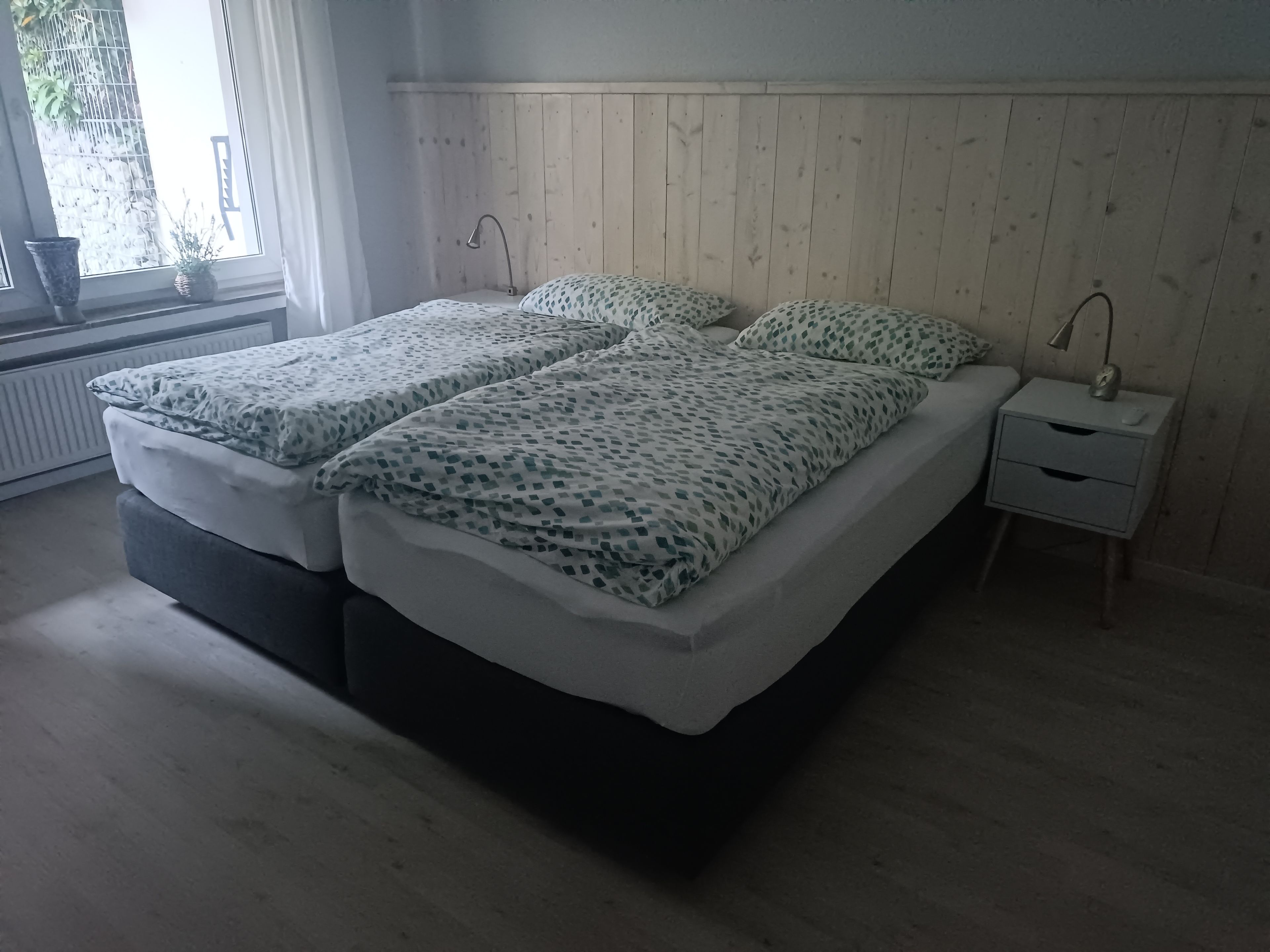 Ein Schlafzimmer mit zwei Betten, einem Nachttisch und einem Fenster mit Blick.
