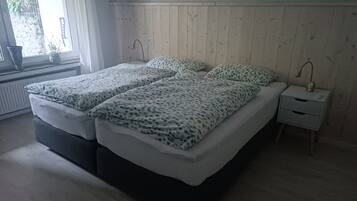Una camera da letto con due letti, un comodino e una finestra vista.