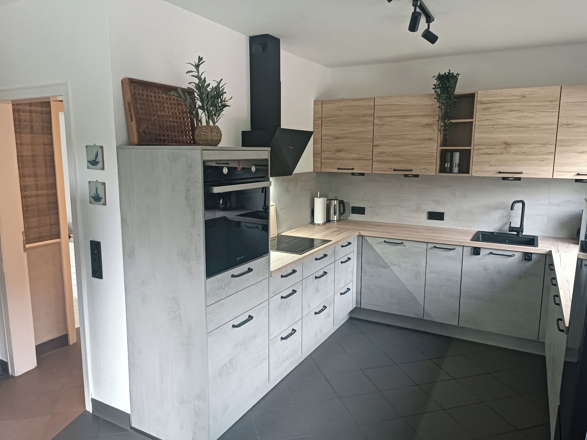 A modern kitchen with a central island, built-in oven, and wooden cabinets.