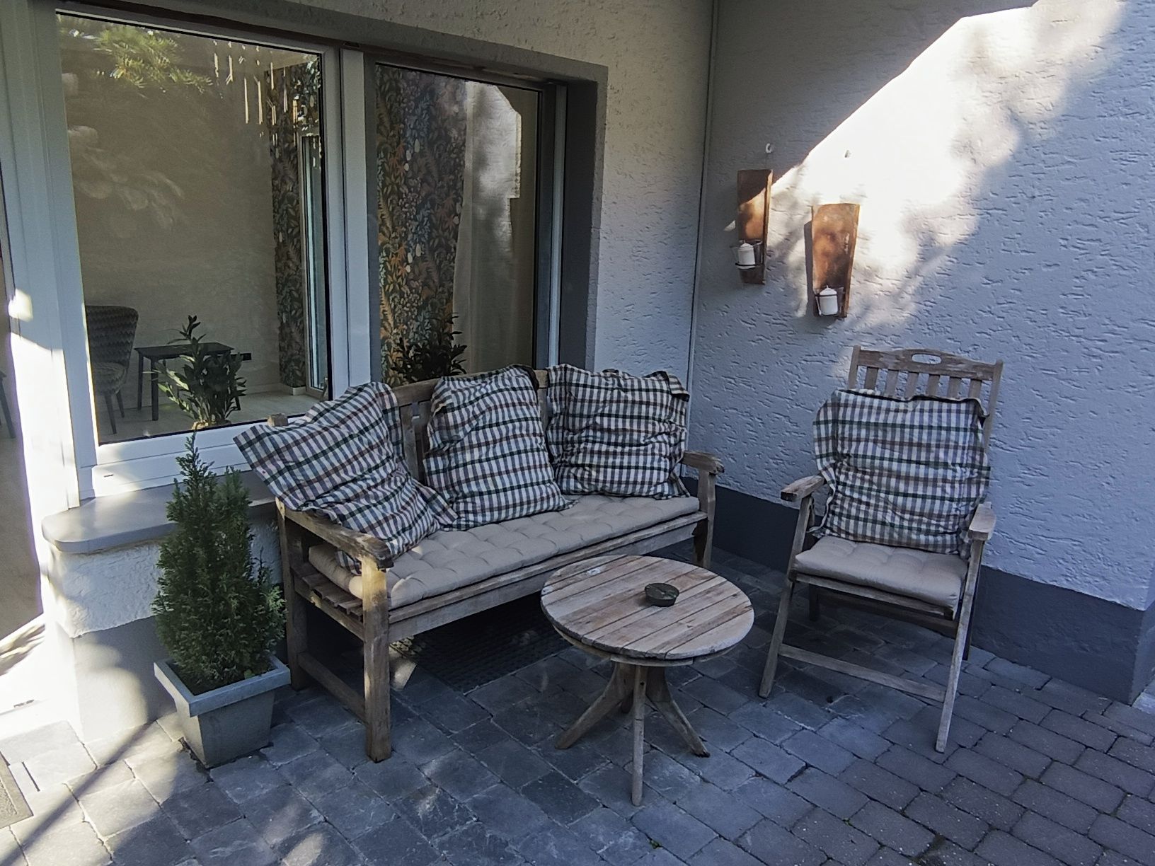 Ein Sitzbereich im Freien mit einer Couch und Stühlen, einem runden Tisch und einem Blumentopf.