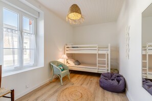 Ein Kinderzimmer mit Etagenbett, einem Korbsessel, einem Sitzsack und einem Wollteppich.