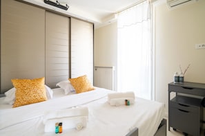 Ett hotellrum med en säng, ett sängbord, ett skrivbord och ett fönster med gardiner.