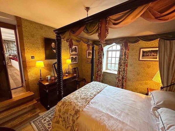 Ein traditionell eingerichtetes Schlafzimmer mit Himmelbett, Schminktisch und Schreibtisch.