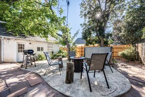 Eine Terrasse im Freien mit einem runden Tisch, Stühlen und einer Feuerstelle.