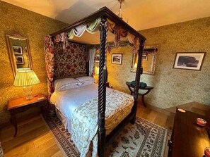 Ein Himmelbett mit Blumentapete und einem gemusterten Teppich.