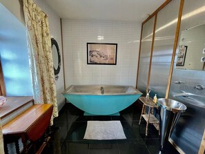 Ein Badezimmer mit einer freistehenden Badewanne, einem Waschbecken und einem Spiegel.