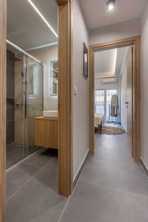 A modern bathroom with a glass shower enclosure, a wooden vanity, and a large mirror. - 3bdr Apartment in Kallithea (Kallithea)