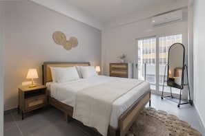 A bedroom with a bed, bedside tables, a dresser, a mirror, and a view through a glass door. - 3bdr Apartment in Kallithea (Kallithea)