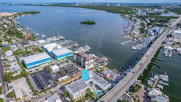 An aerial view of a coastal marina with boats, a bridge, and buildings.