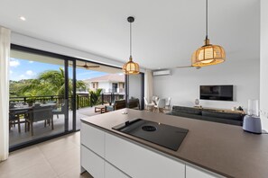 A modern kitchen with a large island, pendant lighting, and a view of the outdoors. - Qasita Quracao - the Breeze Blue Bay Resort (Sint Michiel)