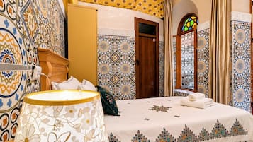 Una habitación con cama, lámpara, paredes con diseño y una ventana con cortinas.