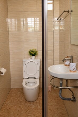 Ein Badezimmer mit Toilette, Waschbecken und einem kleinen Topfpflanzen.
