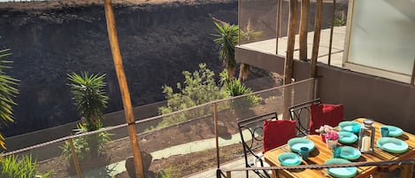 A terrace with a table set for dining, overlooking a mountainous landscape.