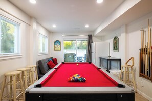 Una mesa de billar con bolas, un sofá y vistas al exterior.