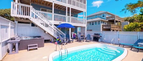 A two-story house with a backyard swimming pool, a barbecue area, and a covered patio with outdoor furniture.