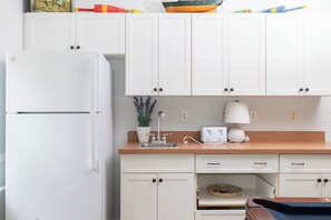 A kitchen with white cabinets, a white refrigerator, a sink, a potted plant, and a lamp. - Corolla Retreat w/ Pool, Hot Tub & Game Rm (Corolla)