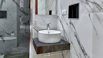 A modern bathroom with a marble sink, a glass shower enclosure, and a mirror.
