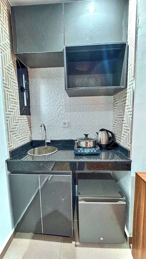 Una cocina compacta con pileta, cocina y heladera pequeña.