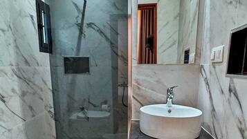 A bathroom with a marble sink, a glass shower enclosure, and a toilet.