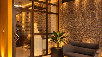 A modern lobby with a geometric patterned floor, a sofa, a potted plant, and a textured wall.