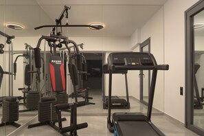 A gym with various exercise equipment, including a treadmill and weight machines. - Dias Grand Villa - Indoor & Outdoor Pools (Bali)
